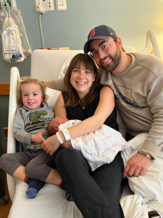 family of four posing in hospital bed after having baby